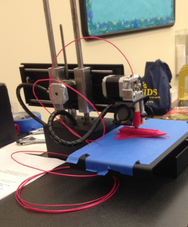 Upper School 3D printer prints a plastic toy airplane in the Levitt Library.
