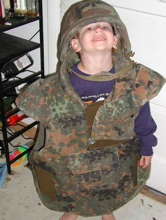 At age four, Firestone proudly wears his father’s Military ensemble. 