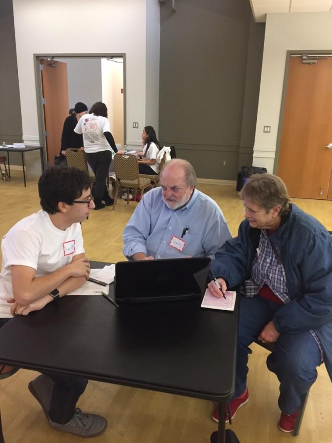 Sophomore Stav Elazar-Mittleman (left) teaches two senior citizens about using technology as part of Families in Action Day.