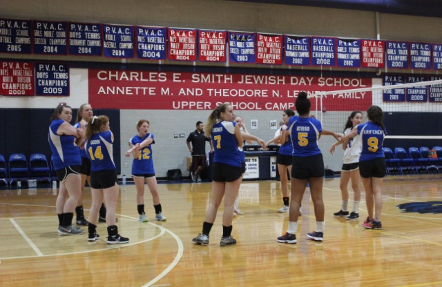 The Girls Varsity Volleyball team participates in a group stretch prior to the Senior Night game. 