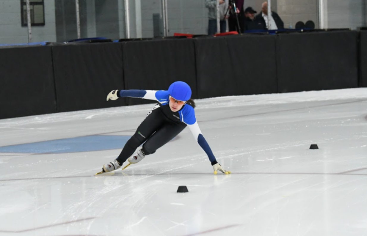 Freshman Ava Fradlin-Ryan rounds a bend in the rink as she speed skates. Like most speed skaters, Fradlin-Ryan stays low down to the ice to push off at a greater angle and gain more speed.