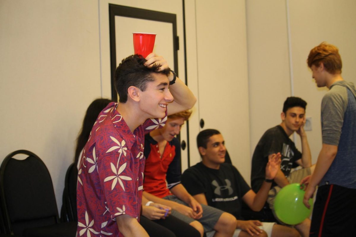 Senior Nick Escobar holds a red cup on his head as his partner prepared to toss a ping pong ball inside of it, as part of a "Minute to Win It" activity.