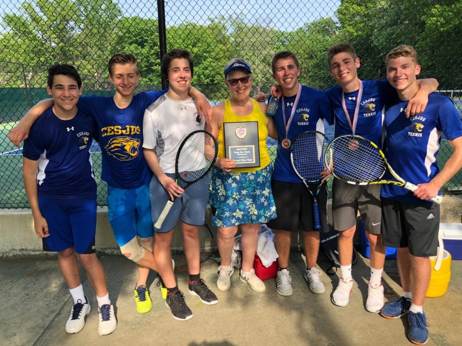 The+boys+varsity+tennis+team+proudly+holds+the+awards+after+their+victories.