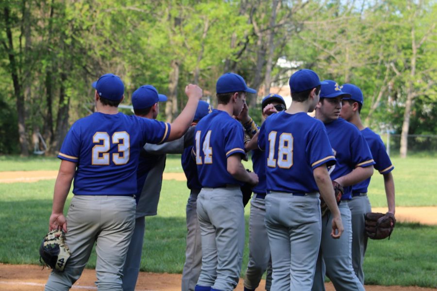 The baseball team gathers during a time-out during a game. 