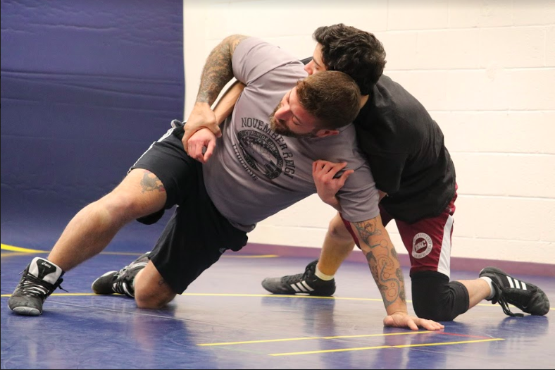 Director of Information Technology and assistant varsity wrestling coach Matthew Castanera- Bartoszek demonstrates a move to junior Adiv Leibestein. Castanera-Bartoszek thinks its valuable to use a hands on coaching approach and show athletes how to do moves.