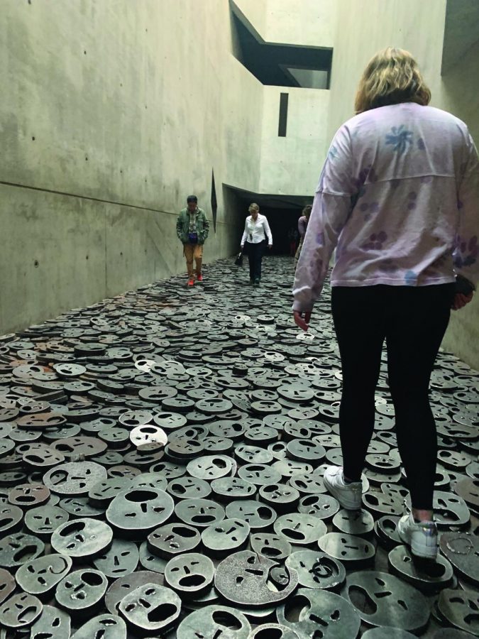 Ambassadors to Germany participant walks among plates of steel faces in the Jewish Museum in Berlin.