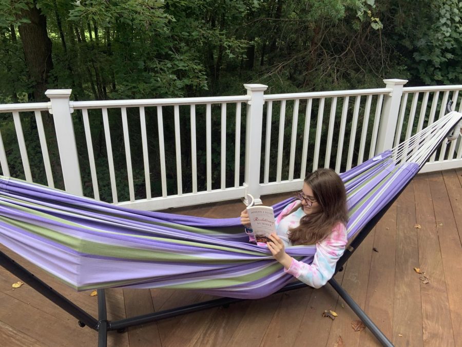 Junior Mira Beinart reads her history summer reading book in a hammock.