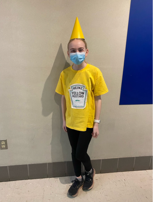 Seventh grader Eve Sharpe geniusly utilizes a yellow party hat to act as the top of her mustard bottle costume. After finding the costume idea on Google, Sharpe and her friend Aliza Braier ventured to Michael’s to buy shirts for their matching ketchup and mustard costumes. Sharpe wears black leggings, a bright yellow shirt with a printed mustard logo taped on and a matching yellow party hat. 