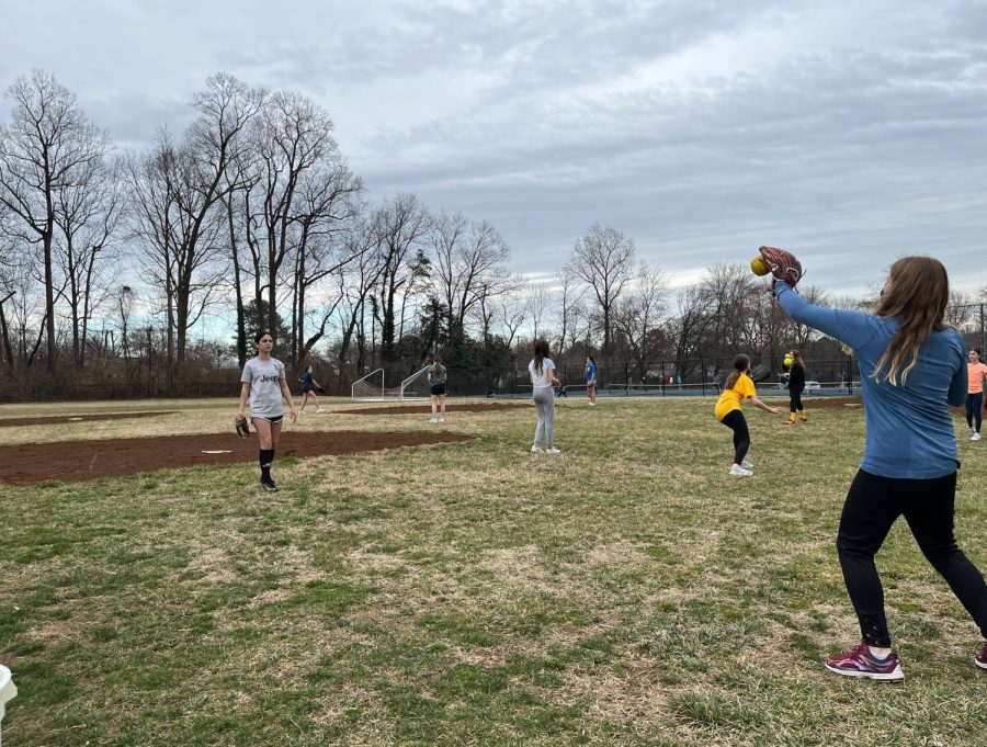 The middle school girls softball team warms up by playing catch. Their coach, high school math teacher Robert Shorr, is looking forward to actually having games for the first time in two years. “Because of the timing of when the pandemic started we only had a couple of practices … that was really disappointing,” Shorr said. 