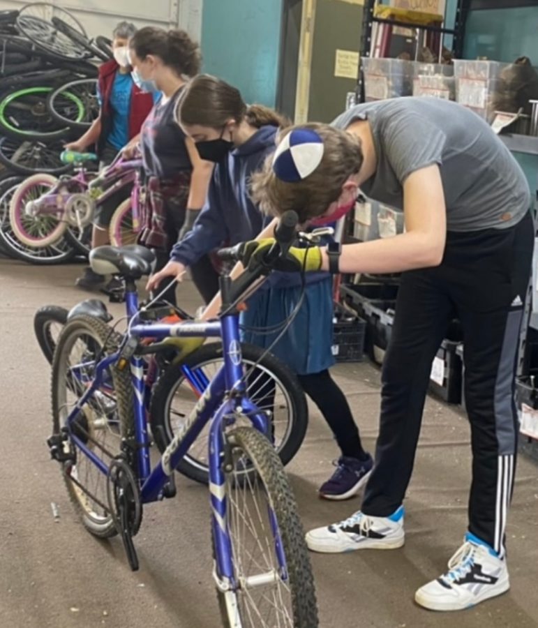 Shess and freshmen Julia Diamond, Michal Nadata and Boaz Dauber bring bikes into the building of the nonprofit in order for them to be taken apart. “Rather than it just sitting in the garage, let’s get it into somebody’s hands and make a difference,” Shess said. 