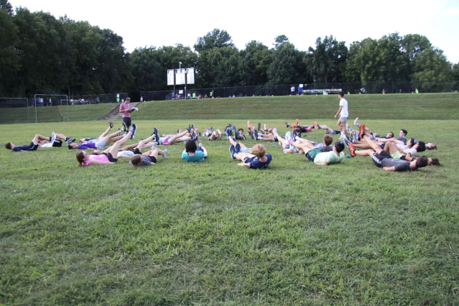Cross country members  participate in a group stretch to cool down after practice. 