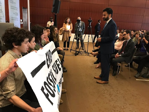 Michael Greenberg (left) along with other members of Climate Defiance display a banner that reads “END FOSSIL FUELS” at the Center for Strategic International Studies after forcing White House Climate Czar Ali Zaidi (right) off the stage. Photo via the Climate Defiance website (used with permission)