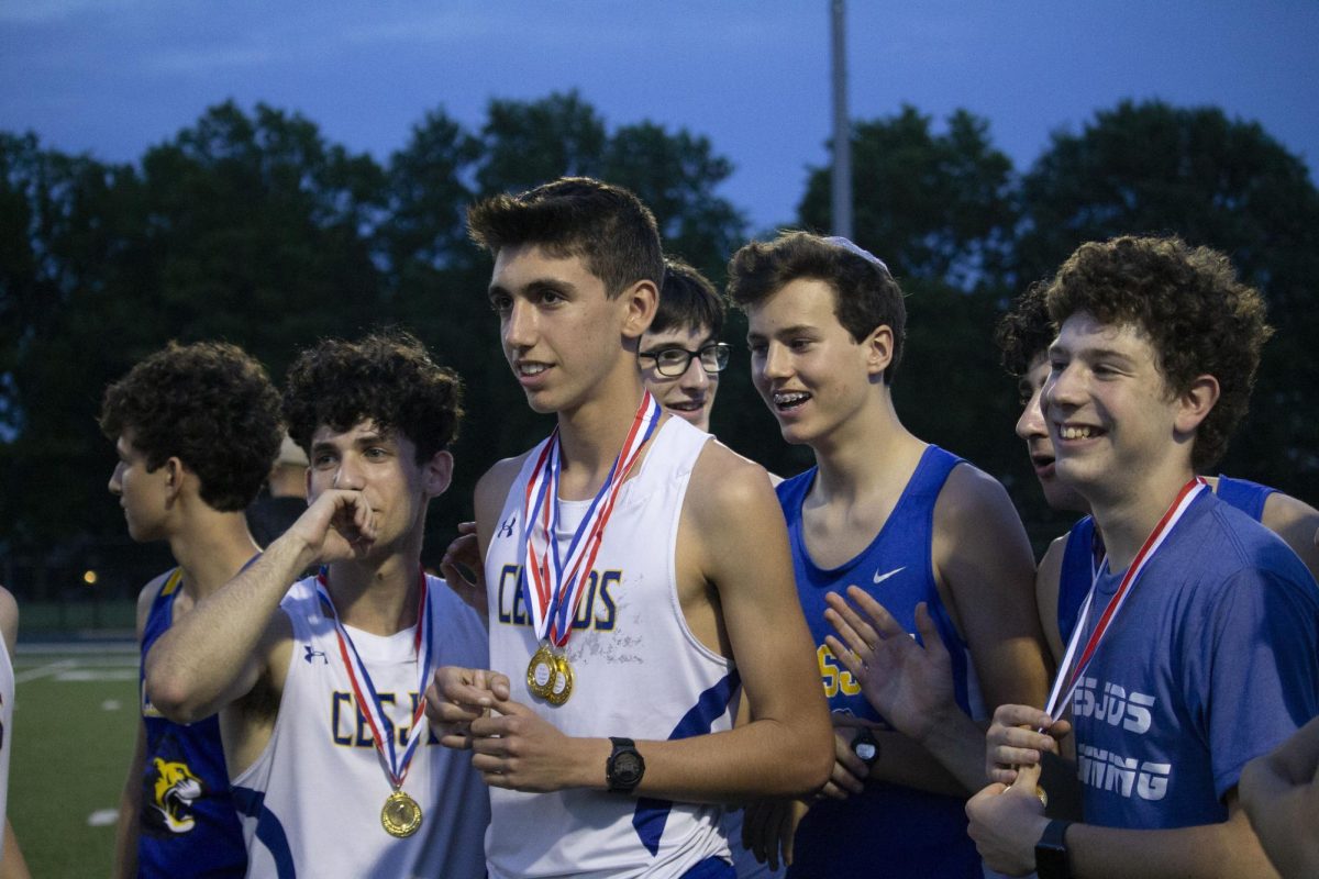 Members of the boys track team listen to the awards ceremony at the end of the championship meet. 