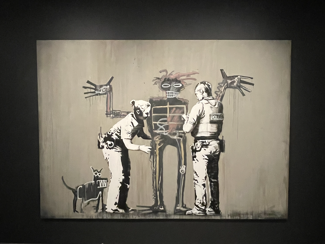 Bansky’s “Basquiat. Boy and dog in Stop and Search” touches on racial inequities faced by Black people in New York. 