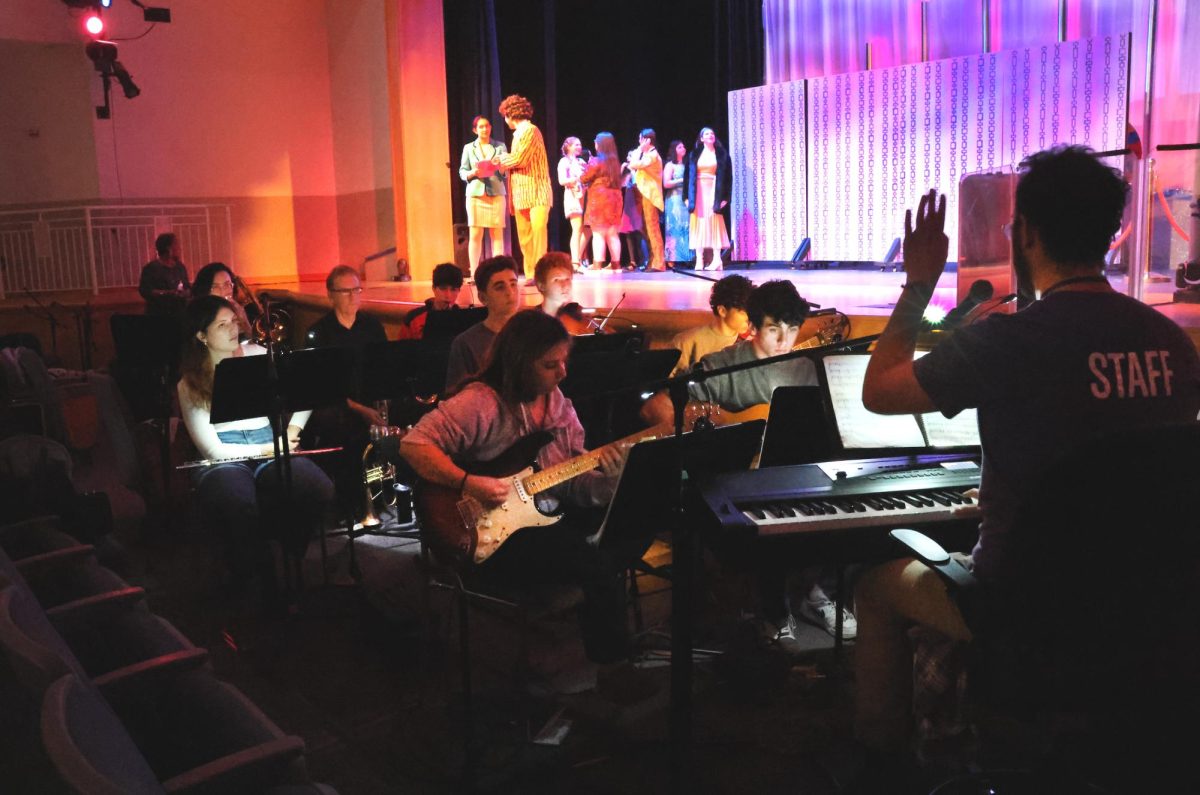 Vocal music and theater teacher Sammy Grob leads the pit band in a dress rehearsal of this year's musical, "Disaster!"