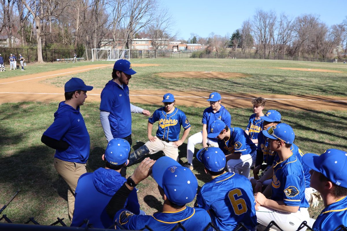 Salomon kneels with the varsity baseball team to discuss strategy before their game against Bullis.