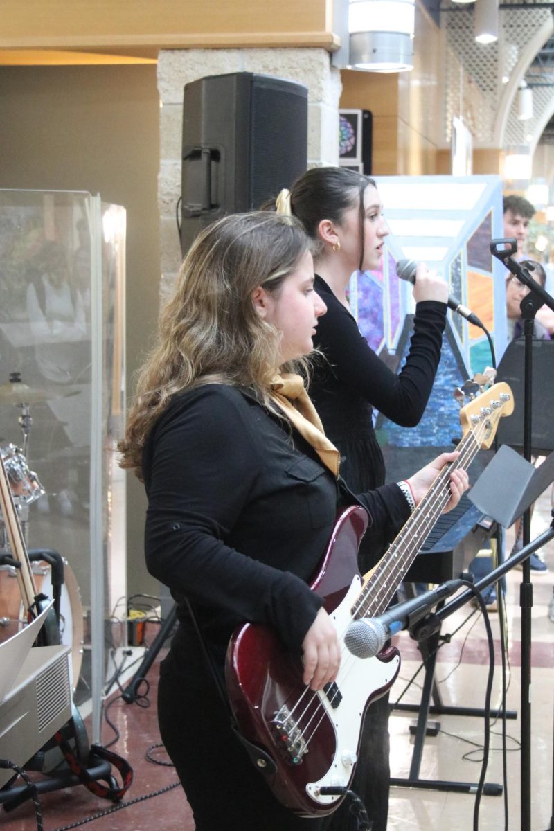 Junior Dara Blecher plays bass by the entryway into Arts Chai-Lights as her parents and members of the JDS community listen and cheer for her. Lee Blecher, father of Dara and fifth grade student Shai Blecher, says that Arts Chai-Lights brings him a lot of joy by seeing his children’s and other students’ confidence that comes from their hard work. As a parent, he said he is very proud to see his kids come out of their shells to express themselves in front of others and that performing provides his kids with a sense of purpose, accomplishment and pleasure. 

Lee and Mia Blecher initiated an endowment to Arts Chai-Lights in honor of their parents. Lee said that his family has always been passionate about music and the arts. He said he is very appreciative of the school for prioritizing the arts in addition to academics, sports and other pursuits since they can get lost. 

“I’m really happy to be affiliated with a school that sees arts as a priority and takes it seriously,” Lee said. “...It just makes this place more well-rounded, and it really gives me a lot of pride that the school sees the importance of every kid and tries to get them to shine in what they’re good at.”

