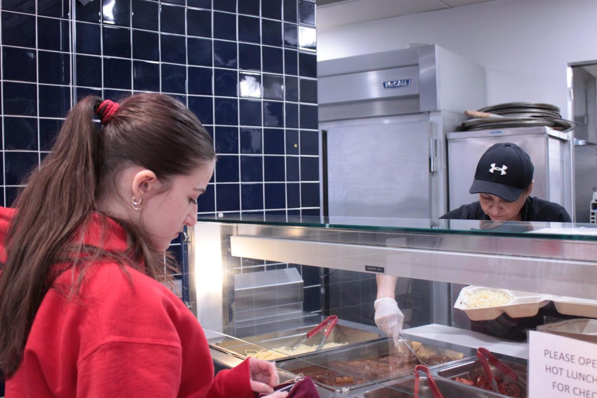 Food services staff member Gloriabelen Lizama serves a lunch of spaghetti and meatballs to freshman Megan Poretsky.