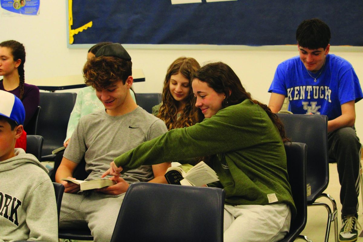 Sophomore Leora Blumenthal helps seventh grade student Riley Blay find
his place in the siddur. 